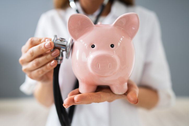 A doctor checks a piggy bank with a stethoscope
