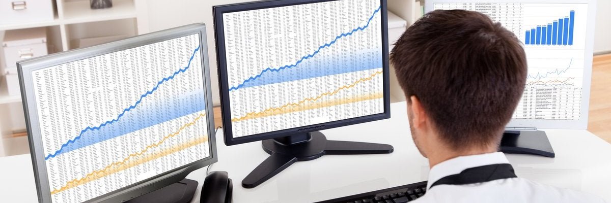 A man viewing charts on multiple computer monitors.