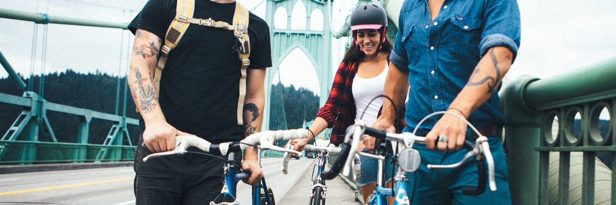 Three people standing next to their bikes and talking while on a bridge in Portland, Oregon.