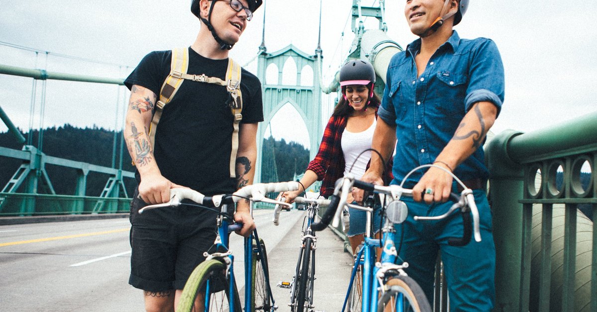 Three people standing next to their bikes and talking while on a bridge in Portland, Oregon.