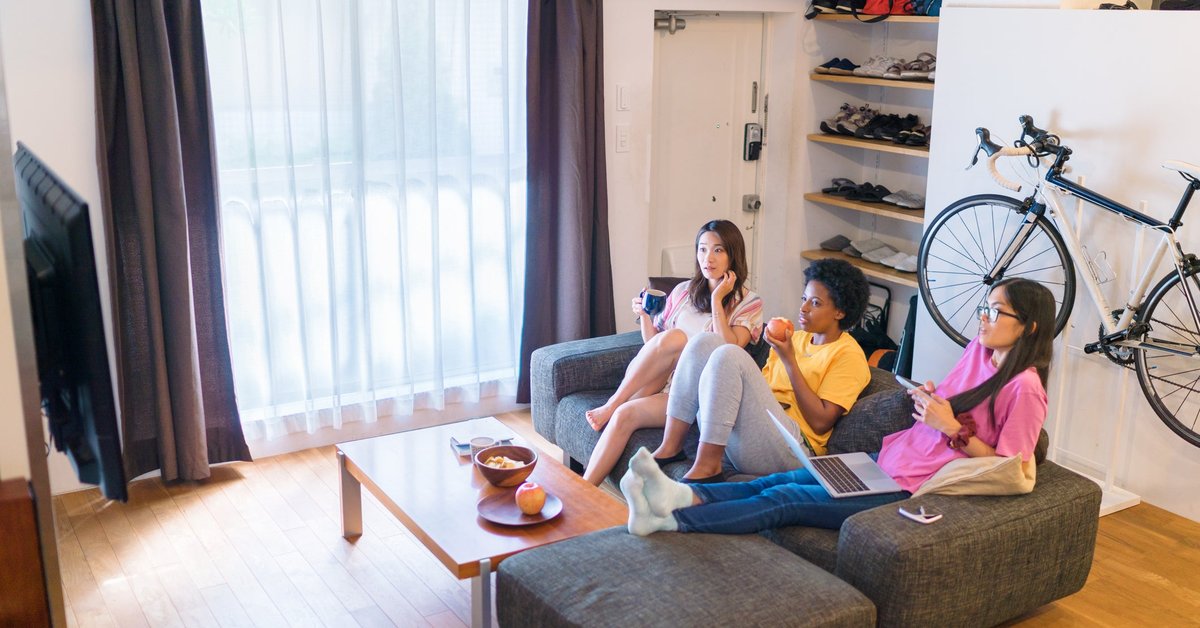 Three roommates sitting on the couch in their apartment.