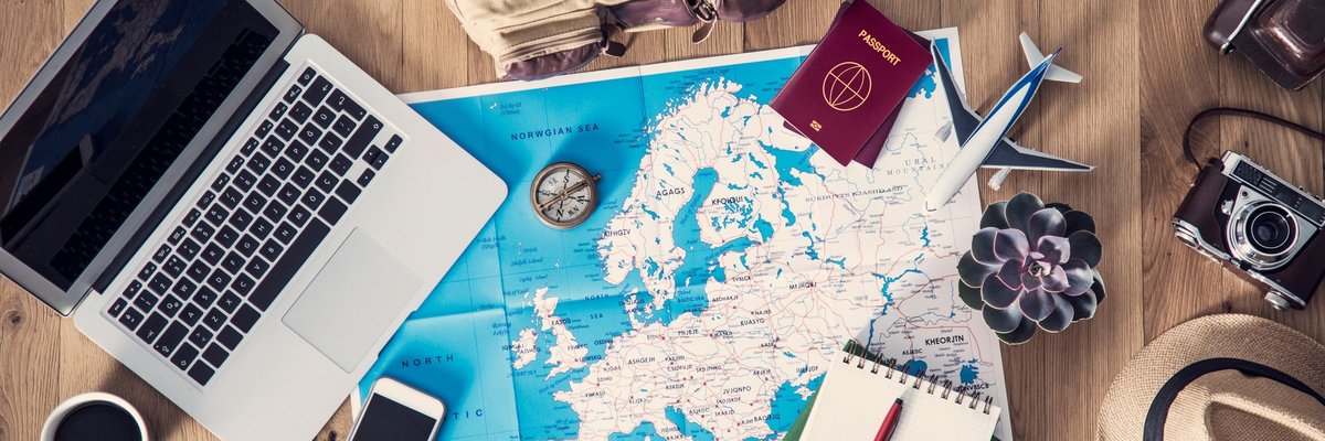 map with computer, notepad, passports, and other travel supplies