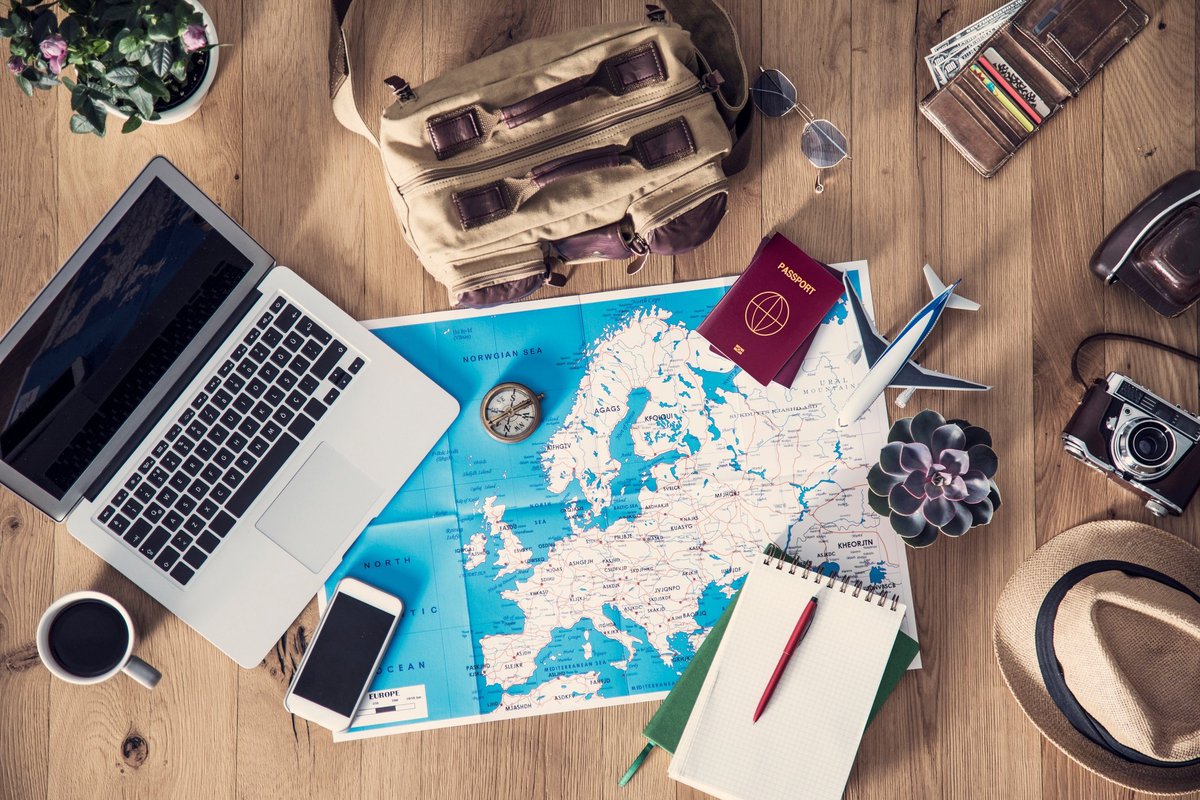 map with computer, notepad, passports, and other travel supplies