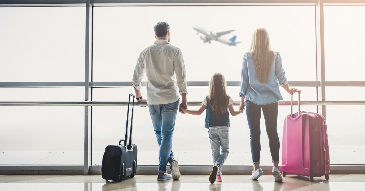 man, woman, and girl holding hands and watching airplane take off