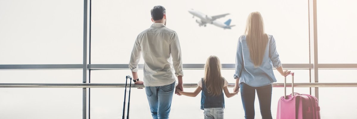 man, woman, and girl holding hands and watching airplane take off