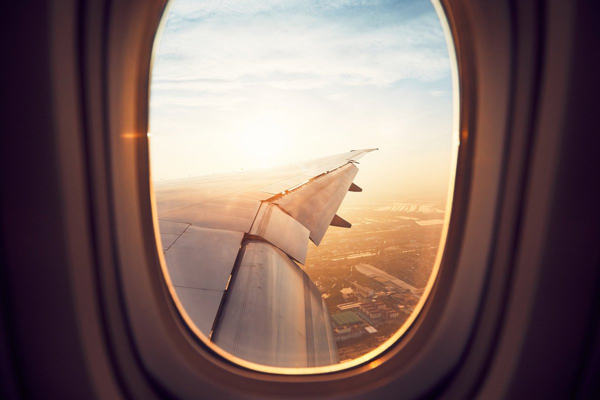 Airplane wing seen through the airplane window flying at sunset