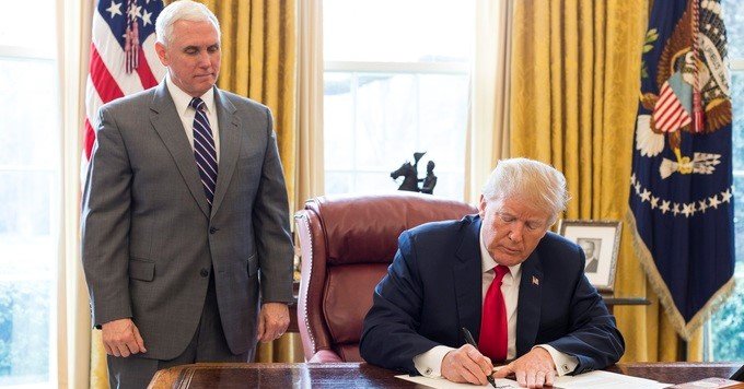 President Trump signing an executive order in the Oval Office.