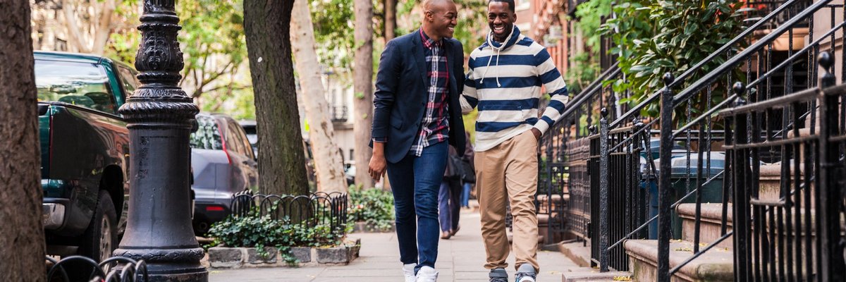 Two men laughing while walking down a residential city street.