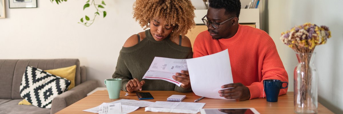Two people sitting at a desk and going over papers while typing in a calculator.