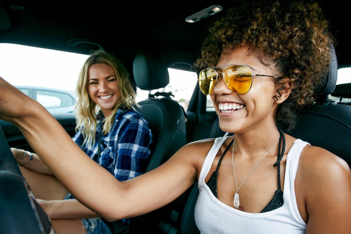 Two smiling people driving in a car.