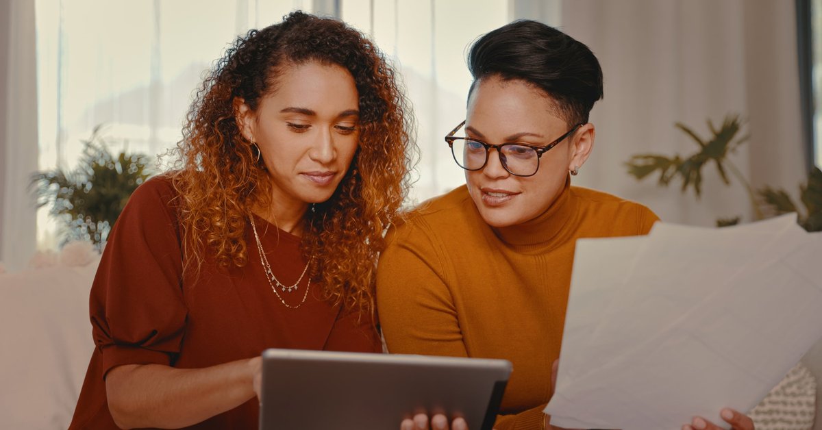 Two people at home looking at a tablet and paperwork.