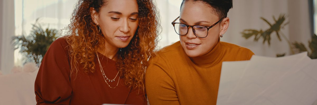 Two people at home looking at a tablet and paperwork.