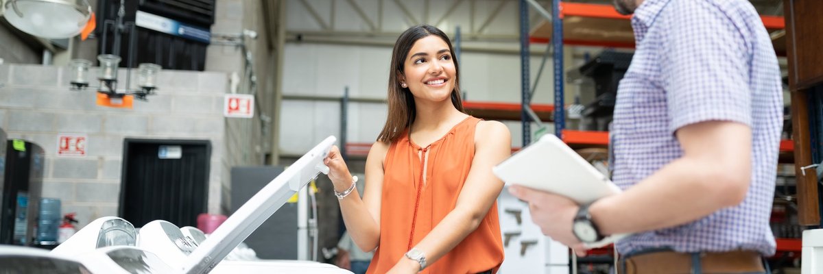 Two people talking next to a washing machine in an appliance store.