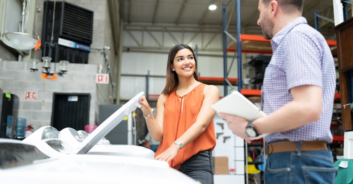 Two people talking next to a washing machine in an appliance store.