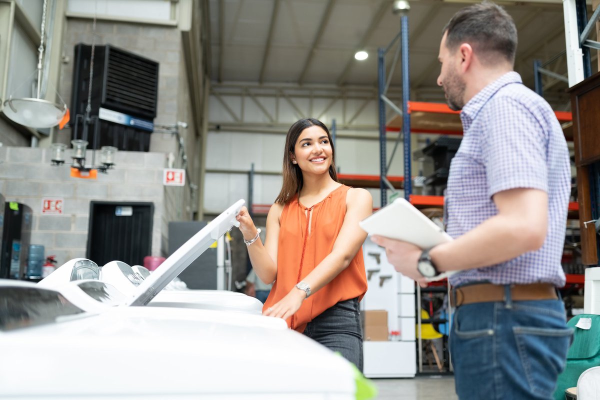 Two people talking next to a washing machine in an appliance store.