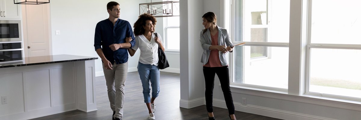 Two people viewing the interior of a house with a realtor.