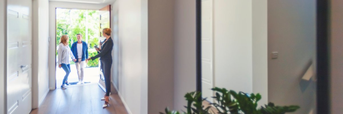 Two people walking in the front door of a house with a Realtor.