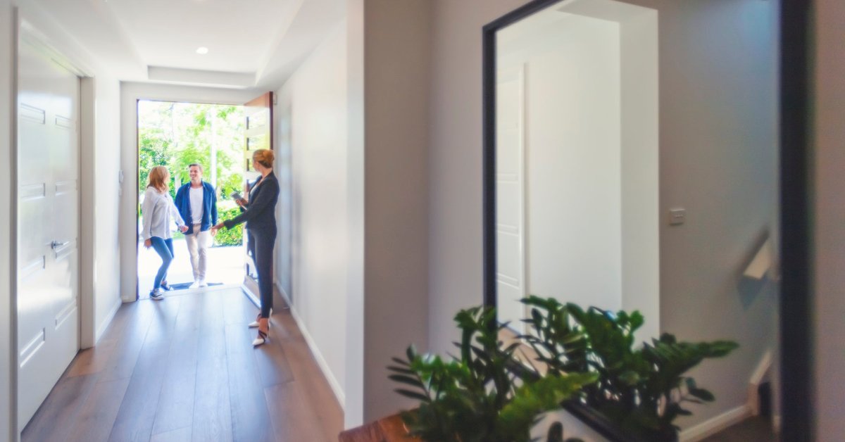 Two people walking in the front door of a house with a Realtor.