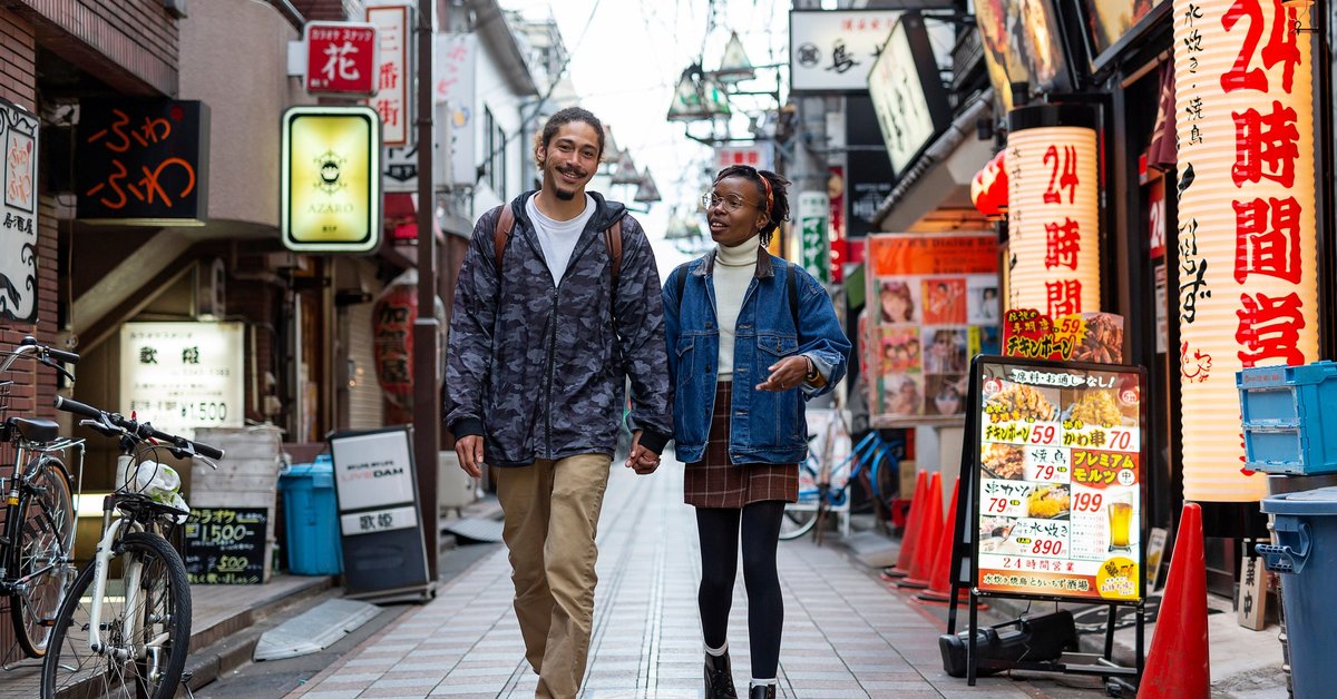Two smiling people holding hands and walking down a small side street in Tokyo, Japan.