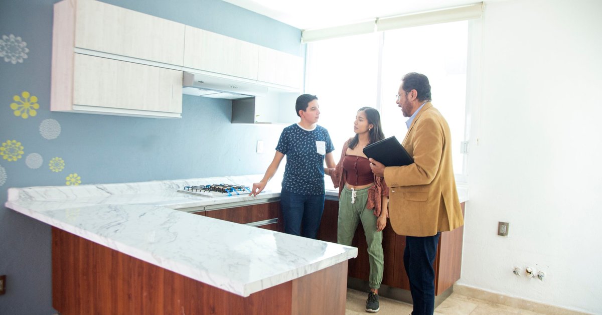 Two people standing in the kitchen of a home for sale with a real estate agent.