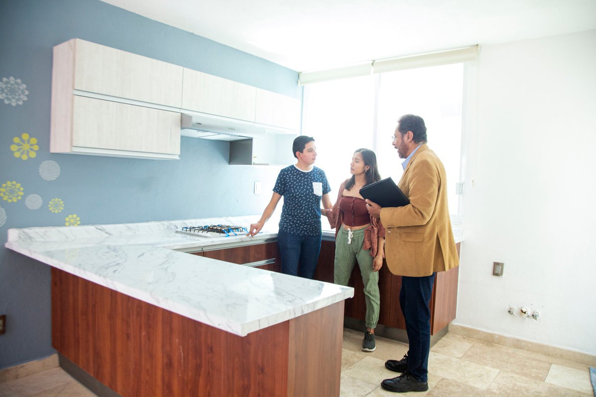 Two people standing in the kitchen of a home for sale with a real estate agent.