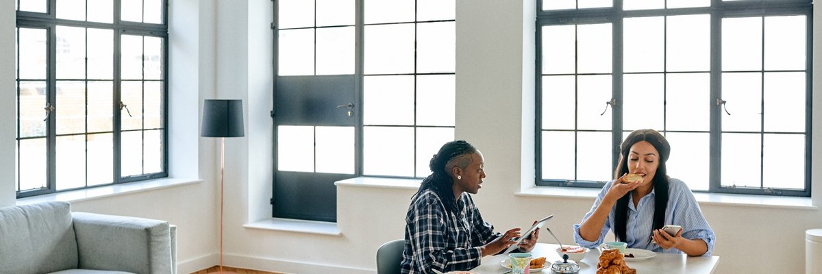 Two women eating breakfast together in their bright loft apartment.