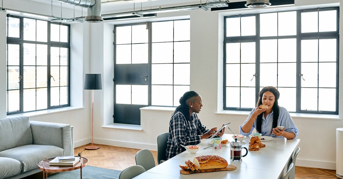 Two women eating breakfast together in their bright loft apartment.