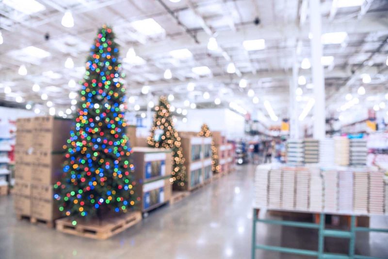 A Christmas tree and other holiday items sit out in a retail store.