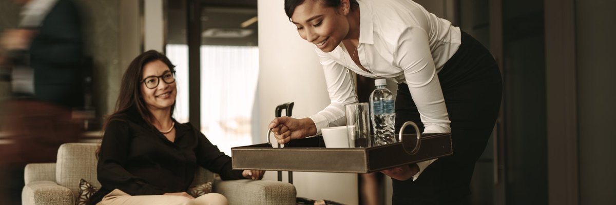 A waitress bringing a tray of drinks to a customer in an airport lounge.