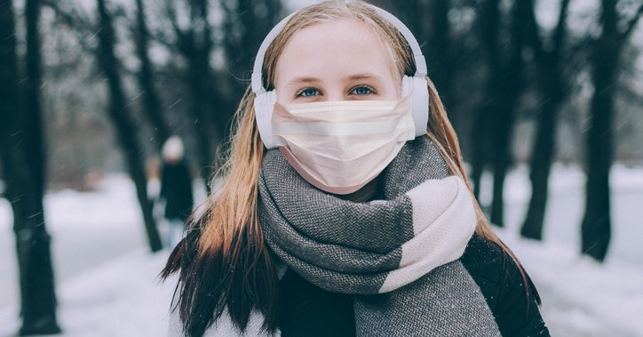 A young woman outdoors in winter wearing a mask