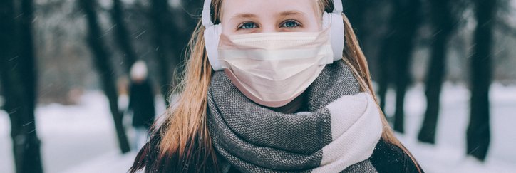 A young woman outdoors in winter wearing a mask