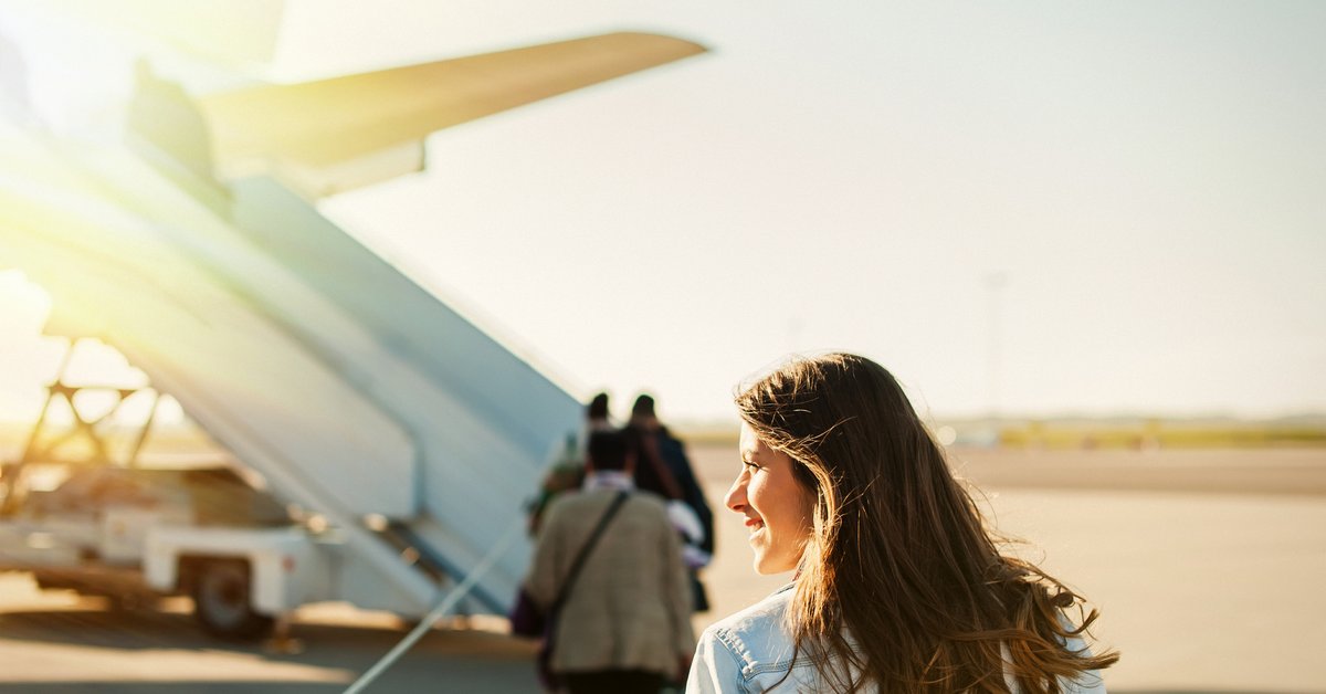 A woman standing on the sunny tarmac and waiting to board a plane.