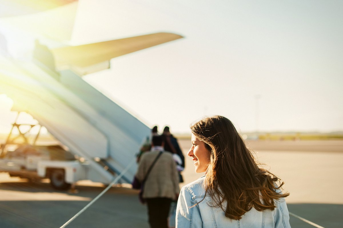 A woman standing on the sunny tarmac and waiting to board a plane.