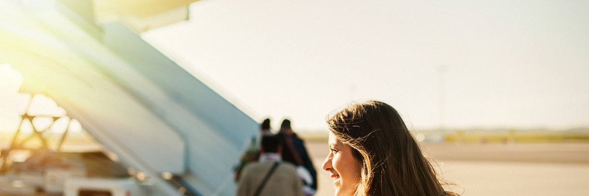 A woman standing on the sunny tarmac and waiting to board a plane.