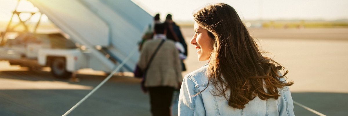 A woman standing on the sunny tarmac and waiting to board a plane.