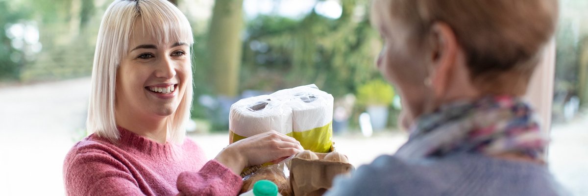 A young woman bringing groceries to an older woman.