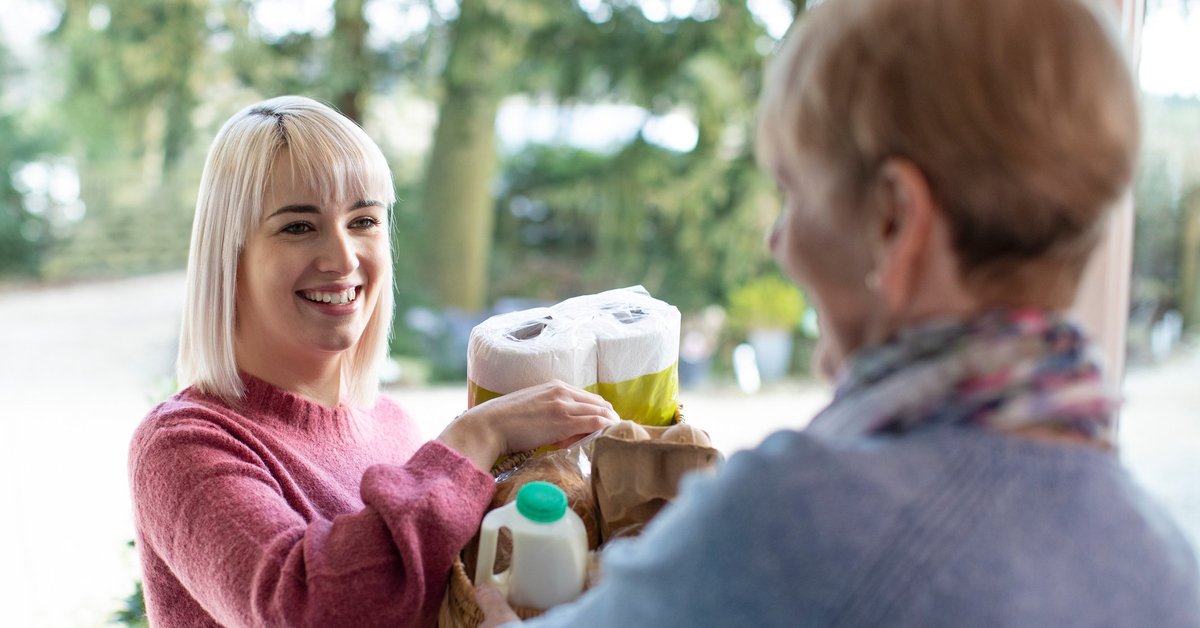 A young woman bringing groceries to an older woman.