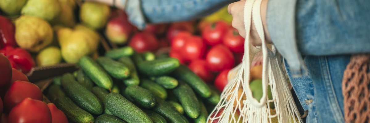 A woman selecting produce at a grocery store.