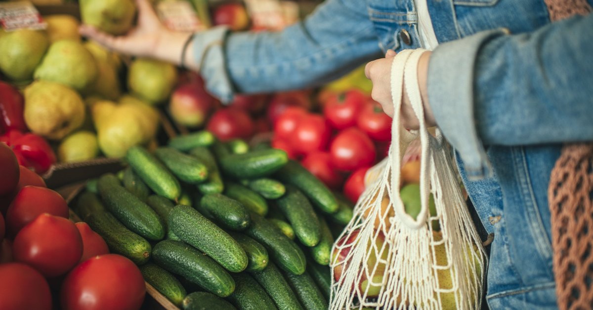 A woman selecting produce at a grocery store.