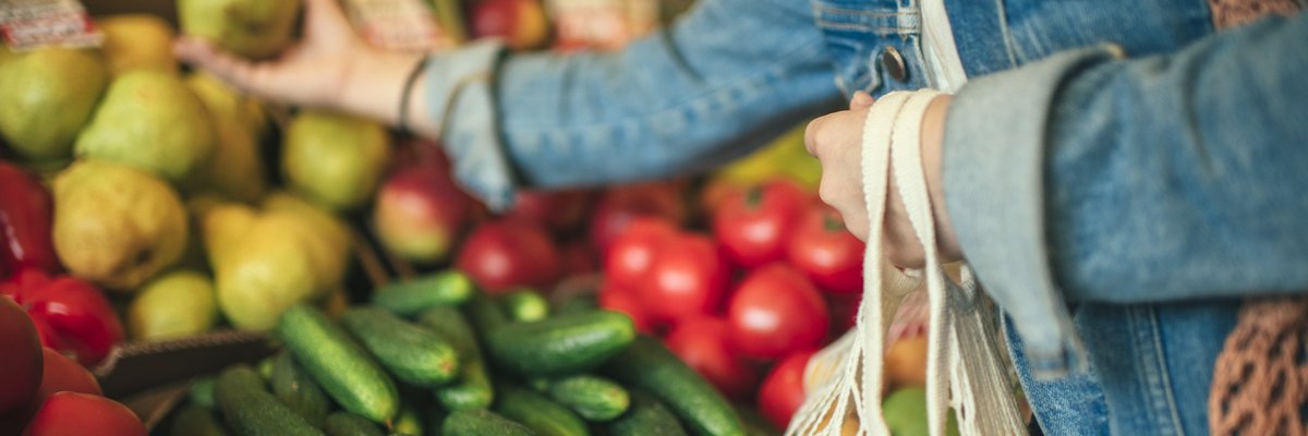 A woman selecting produce at a grocery store.