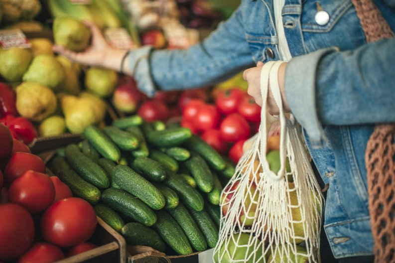A woman selecting produce at a grocery store.