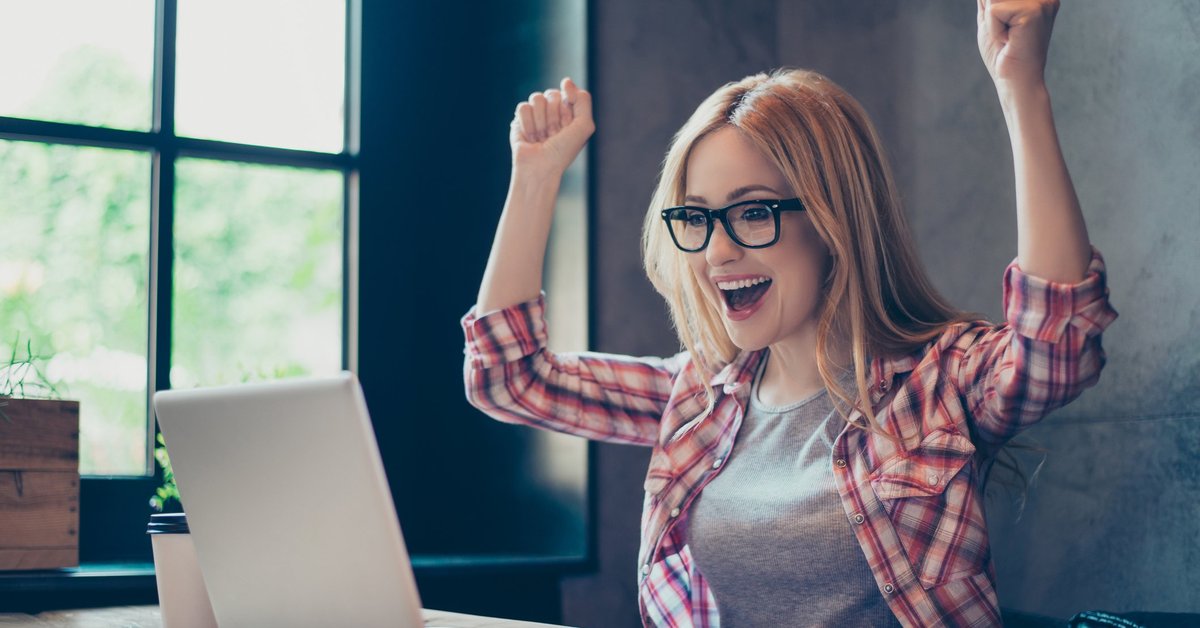 Young woman celebrating at laptop