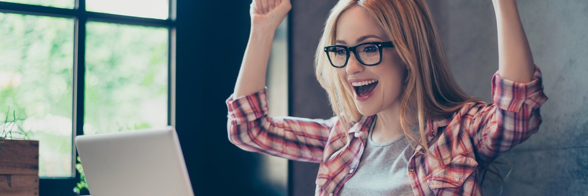 Young woman celebrating at laptop