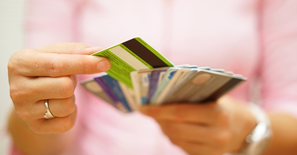 Woman choosing one credit card from a handful of many cards