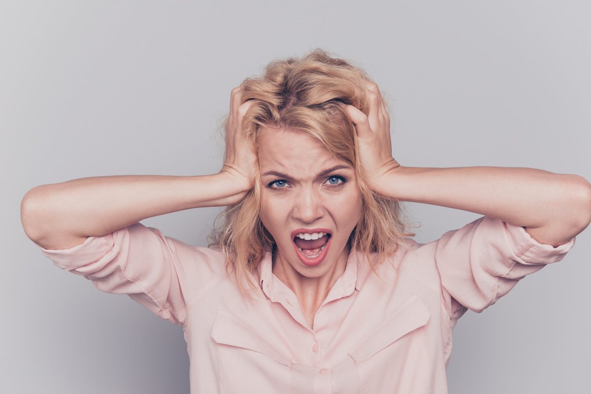 Woman holding her head with angry expression on her face.