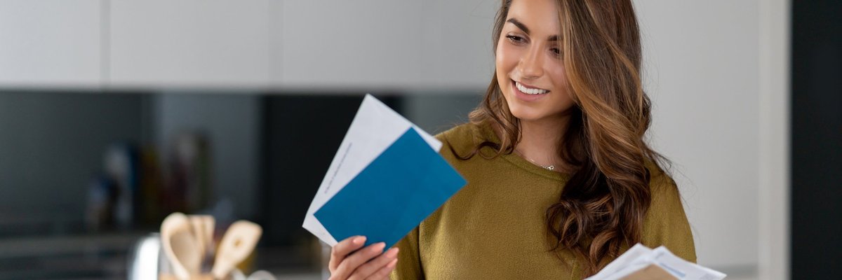 A woman holding her mail while standing in her kitchen.