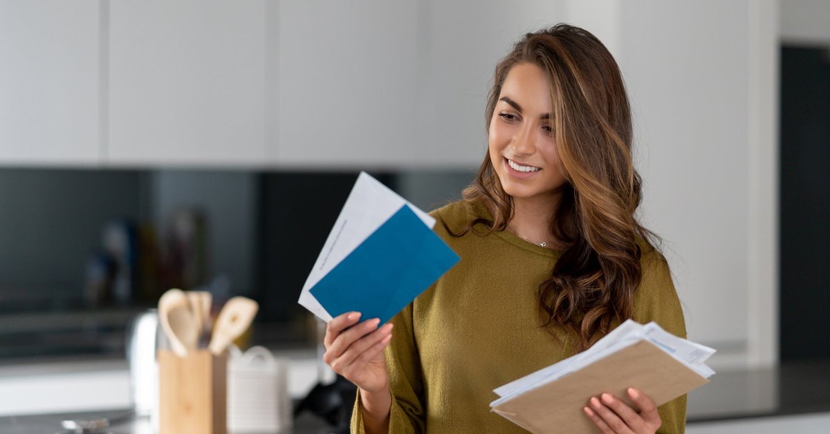 A woman holding her mail while standing in her kitchen.