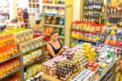 A woman looking at jars of food in an empty grocery store.