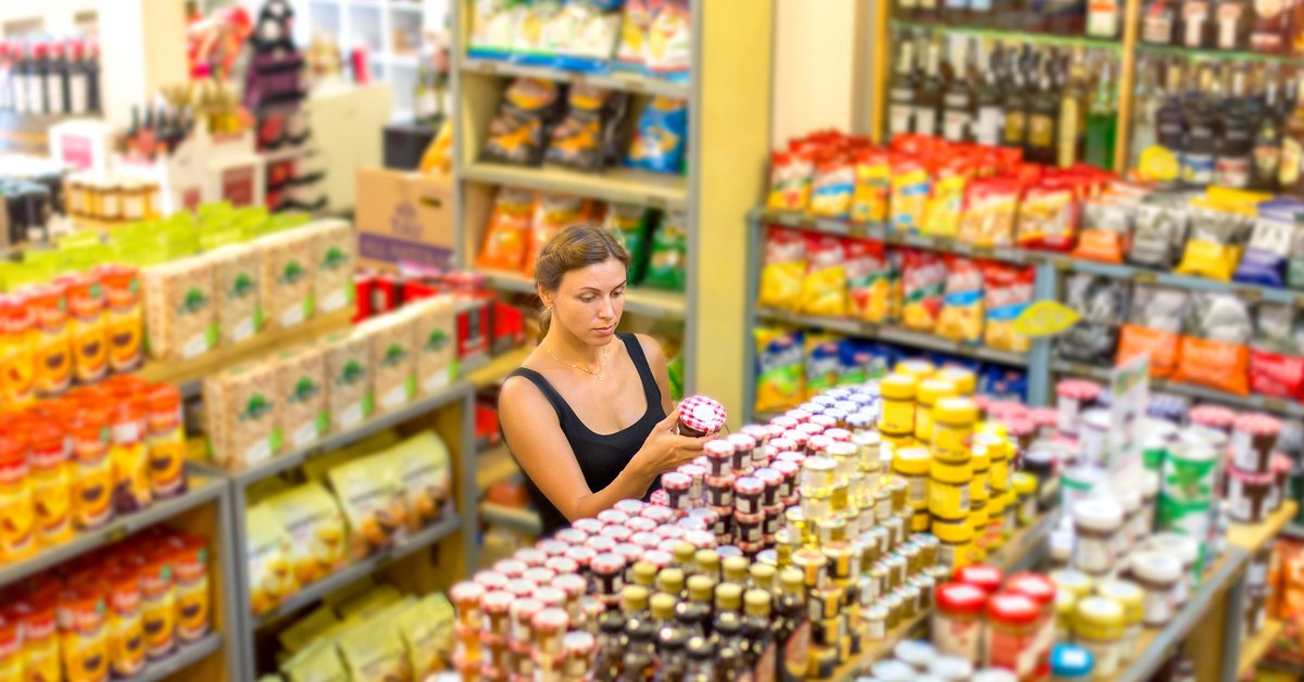 A woman looking at jars of food in an empty grocery store.