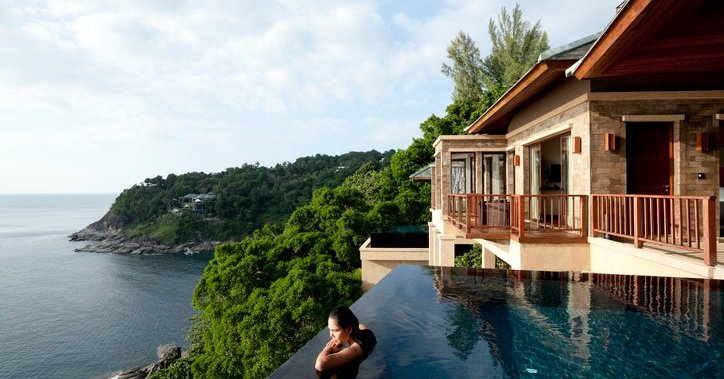 A woman in a pool at a luxury hotel overlooking the ocean.
